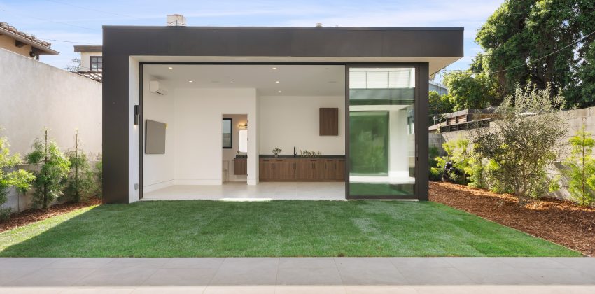 New custom home rear exterior with large sliding glass door and landscaped backyard in Manhattan Beach, CA
