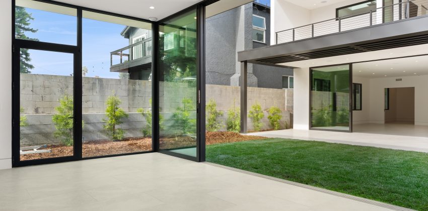 Modern two-story custom home with floor-to-ceiling glass sliding doors, courtyard, and balcony in Manhattan Beach, CA