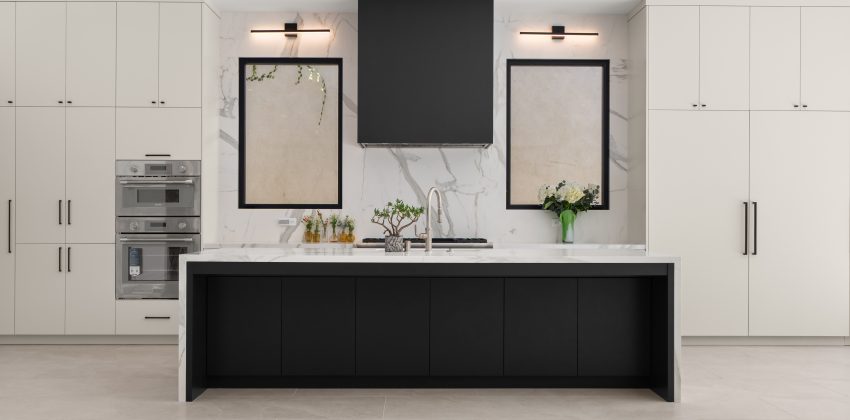 Modern kitchen with black waterfall island, white cabinetry, and marble backsplash in a Manhattan Beach custom home