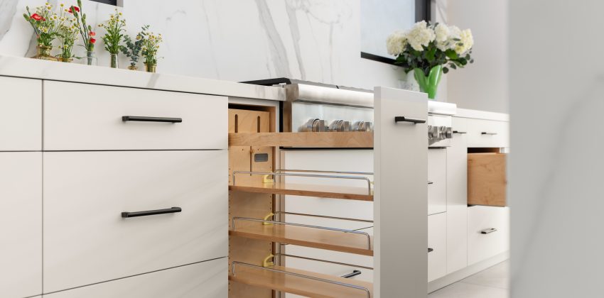 White kitchen cabinetry with pull-out wood pantry organizer and matte black hardware in Manhattan Beach home