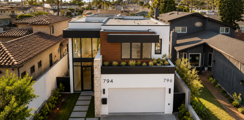 Aerial view of modern new custom home with dark stucco, wood accents, and rooftop deck in Manhattan Beach, CA